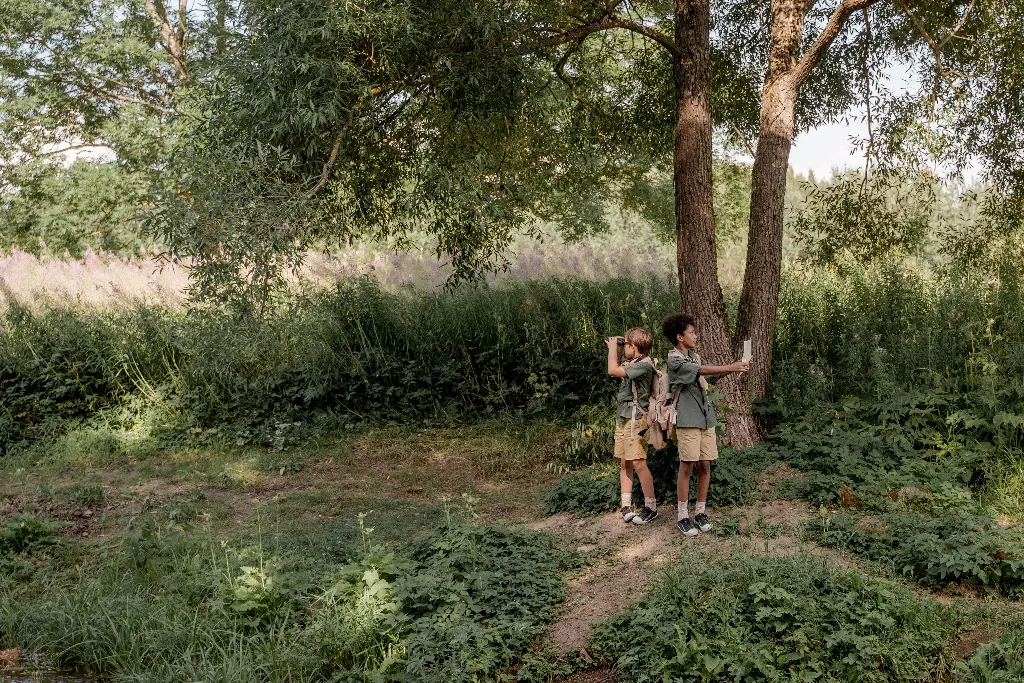 Two kids exploring nature with binoculars and map. Kids having adventure in outdoors.